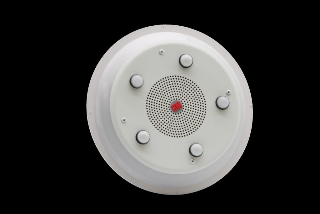 RadioMobile (RMI) Crew Alert Module (CAM) fire station alerting device in non-alert mode, featuring a central speaker and five circular light indicators.
